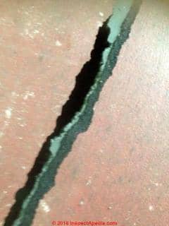Tear in red backed Congoleum art rug shows asphalt-impregnated backer that may contain asbestos (C) InspectApedia.com Jennifer McKen na