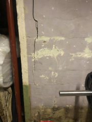 Vertical crack near inside corner of a concrete block foundation wall (C) InspectApedia.com Kim